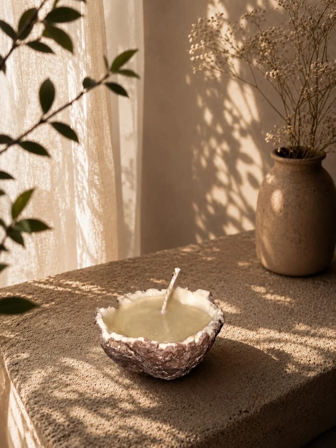 Candle poured into a natural coconut half shell on a stone ledge