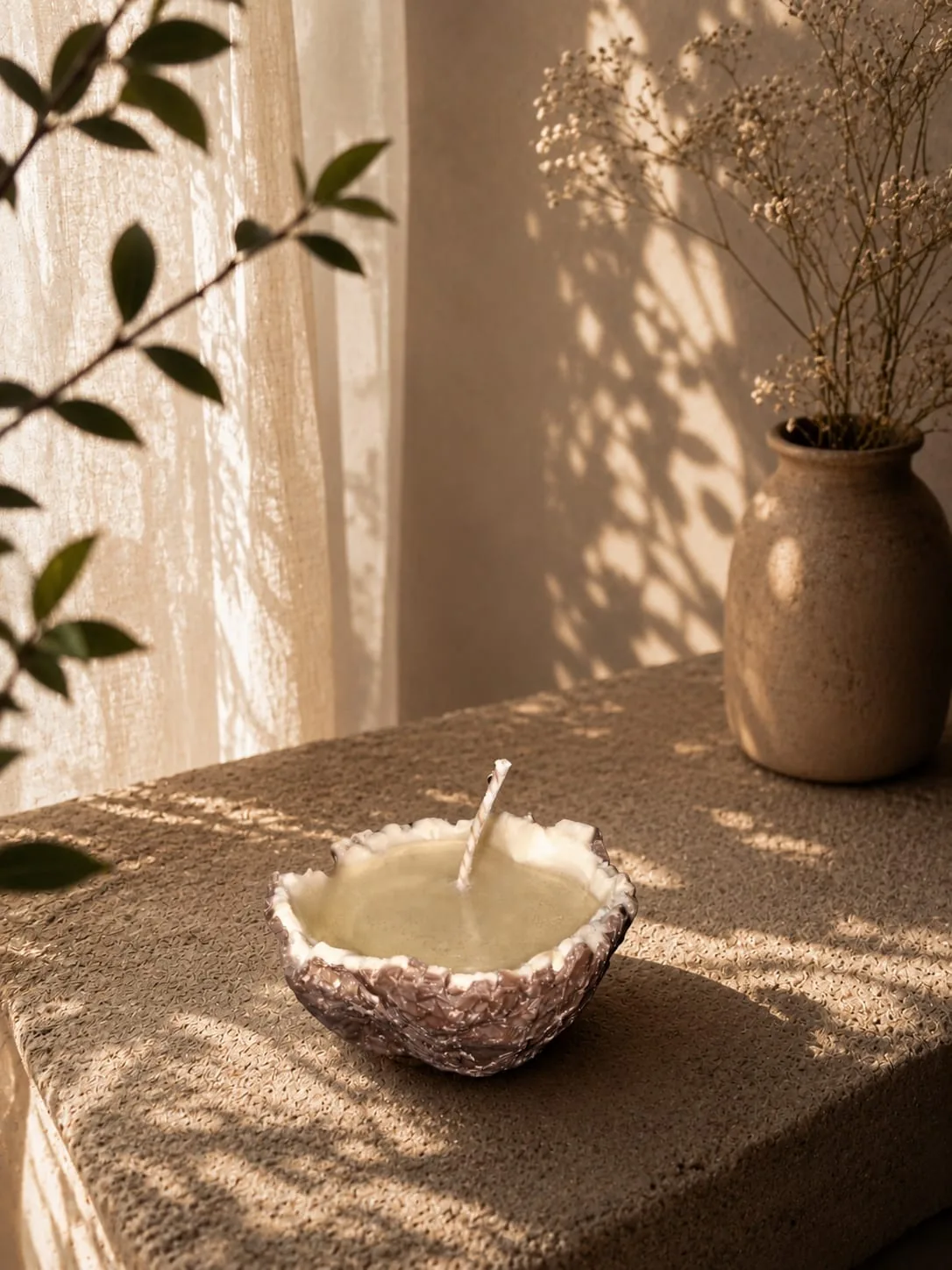 Candle poured into a natural coconut half shell on a stone ledge